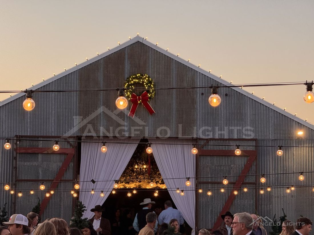 String lights across a barn at an evening event