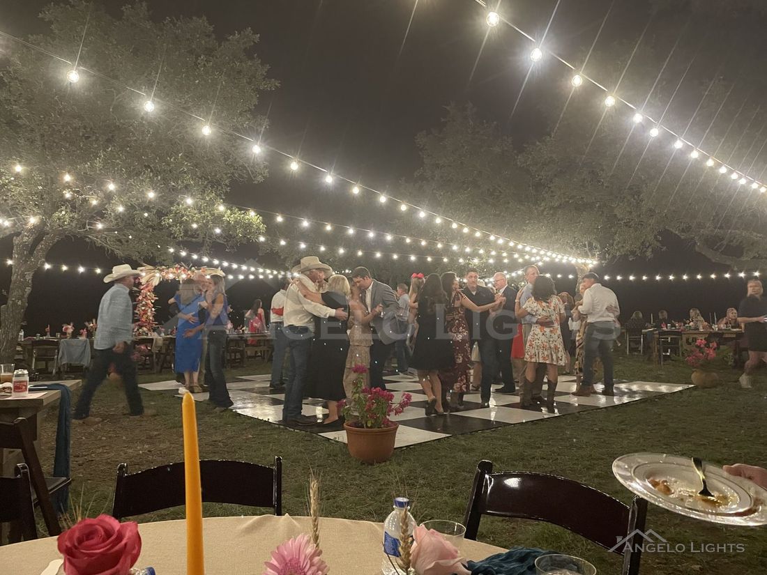 Guests dancing under string lights at an outdoor celebration