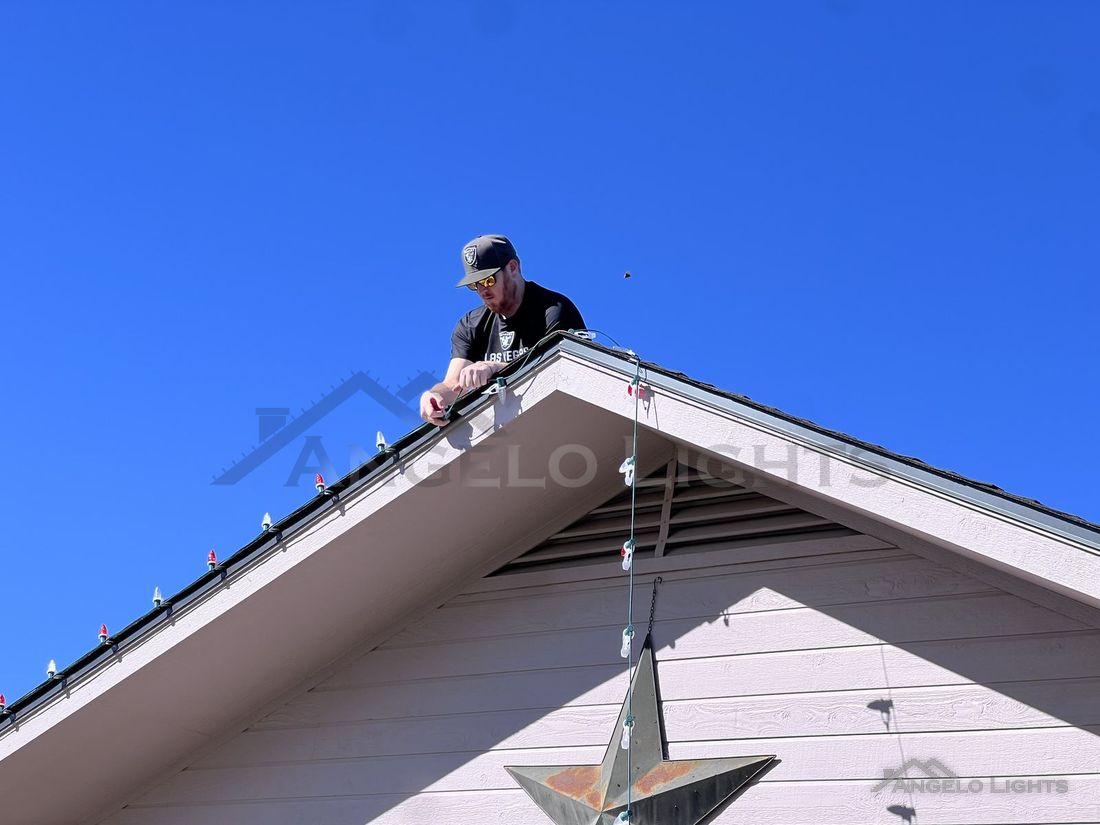 Angelo Lights installer clipping lights along a roof gable