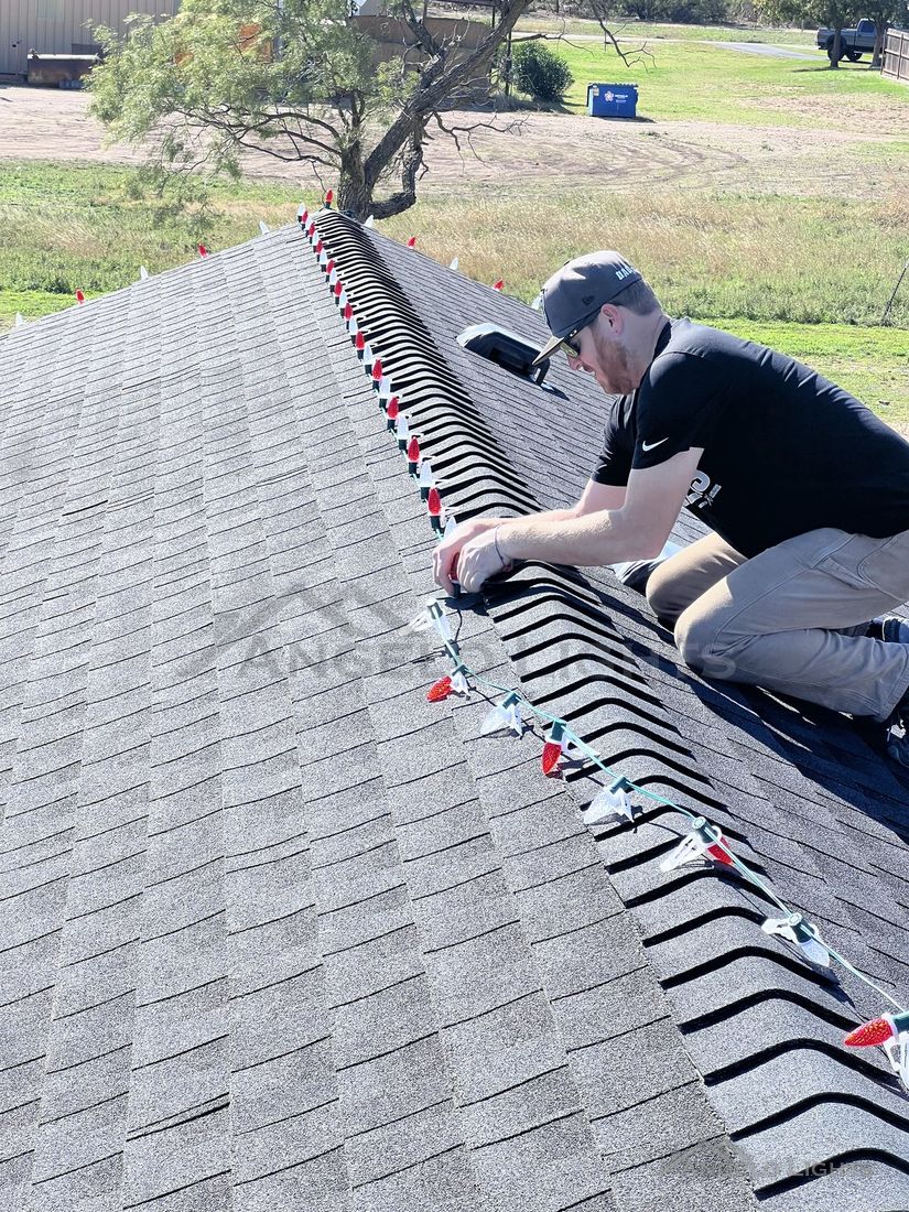 Installer clipping lights along a roof ridge