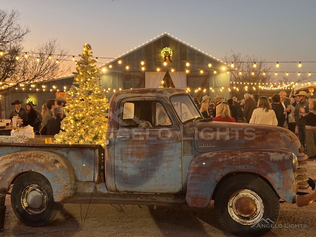 Vintage truck and Christmas tree under string lights at an event